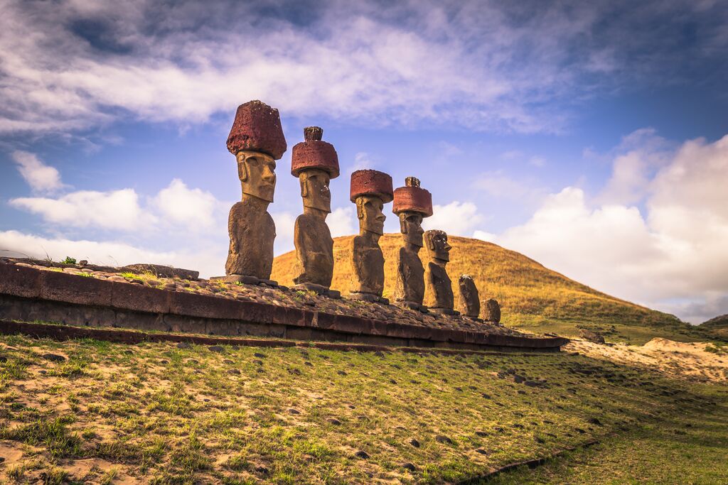 Stone monuments in easter island, with a hill in the background