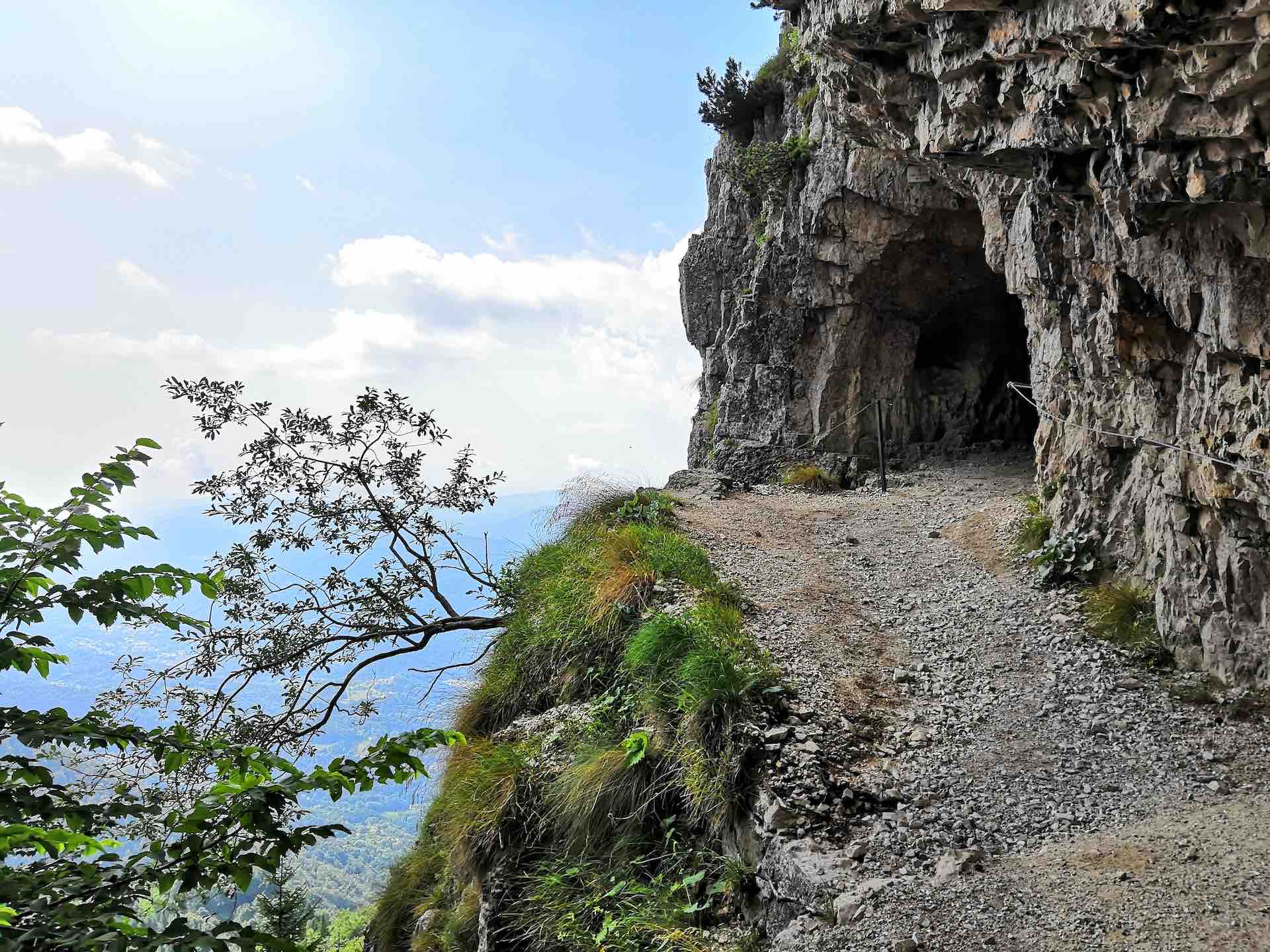 A cliffside path leading to a tunnel in the side of the mountain
