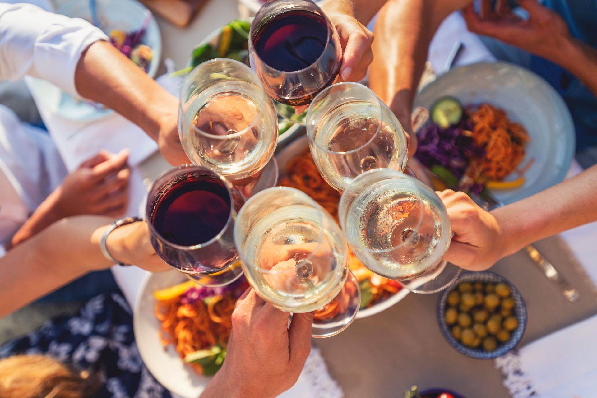 A group of people cheersing with wine over dinner on a sunny day
