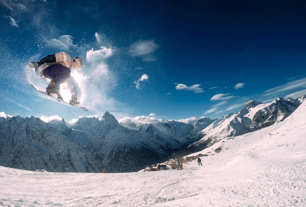 A snowboarded jumping in the air on the snowy mountain slopes