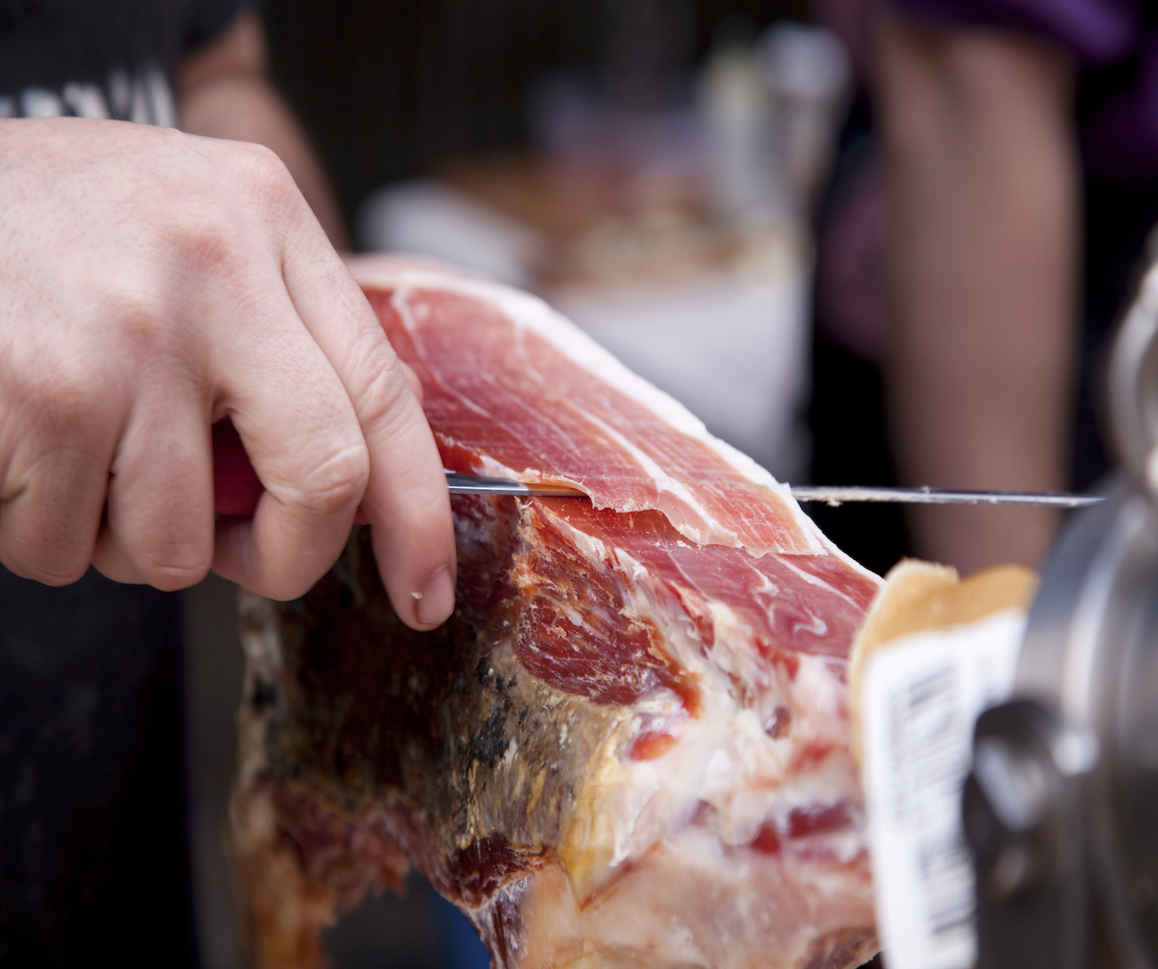Closeup of someone cutting a slice of cooked ham