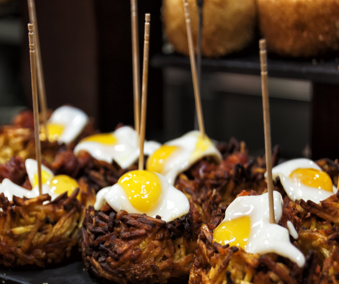 Closeup of fried potato balls with an egg on top of each one