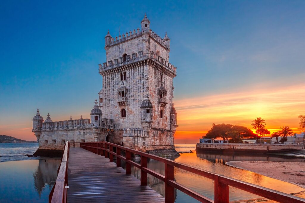 The castle-like Belem Tower at sunset, with the water behind.