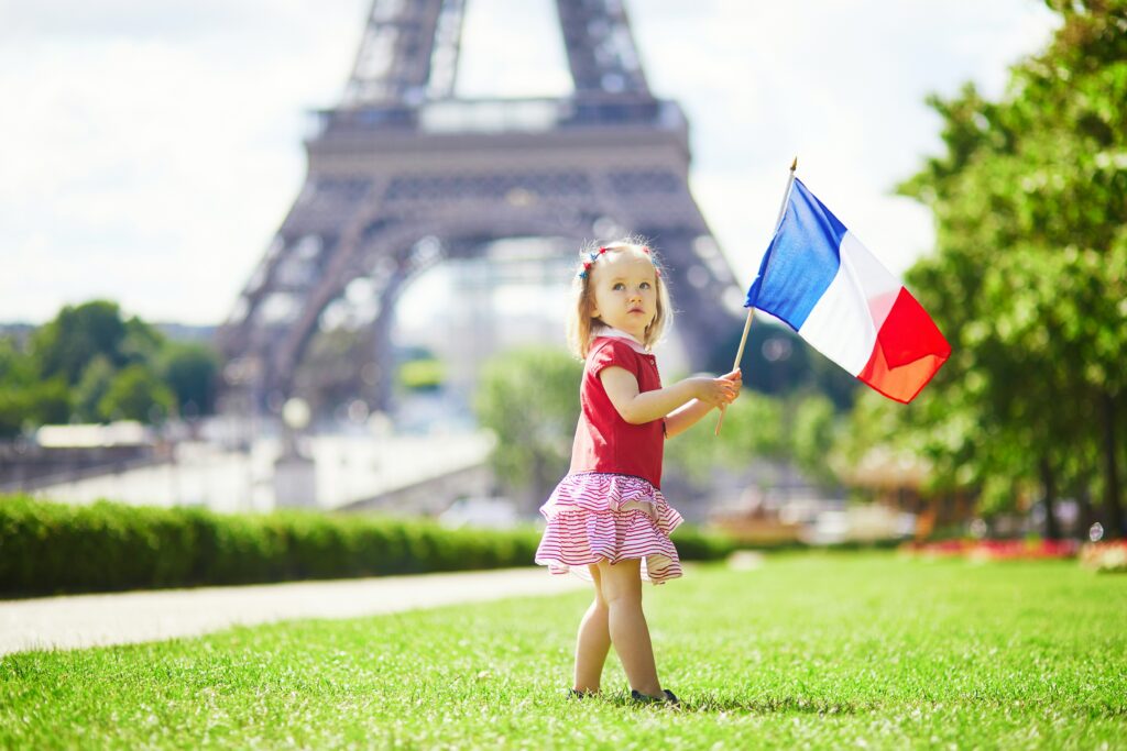Child holding French flag in front of the Eiffel Tower