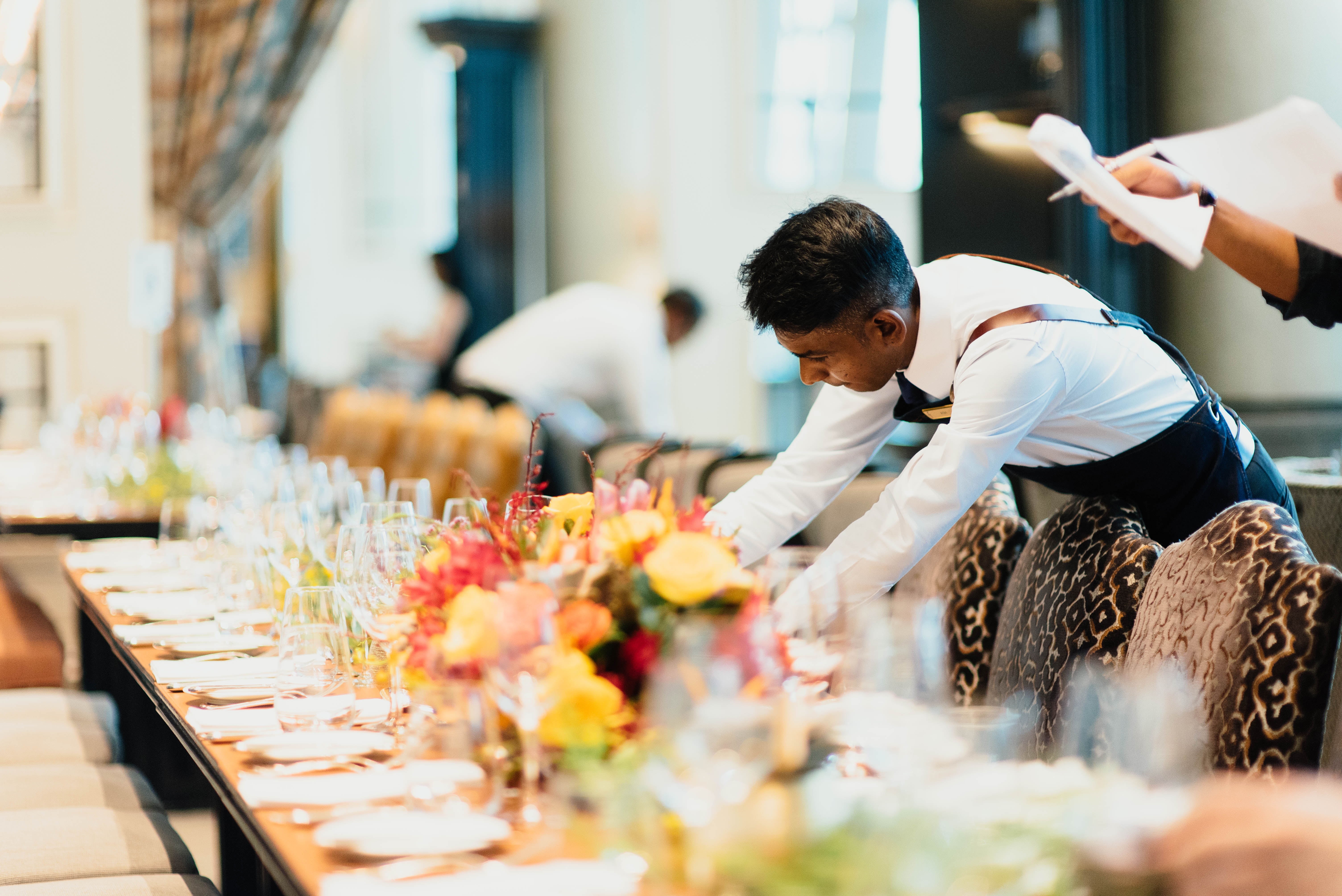 Young man setting tables in a restaurant