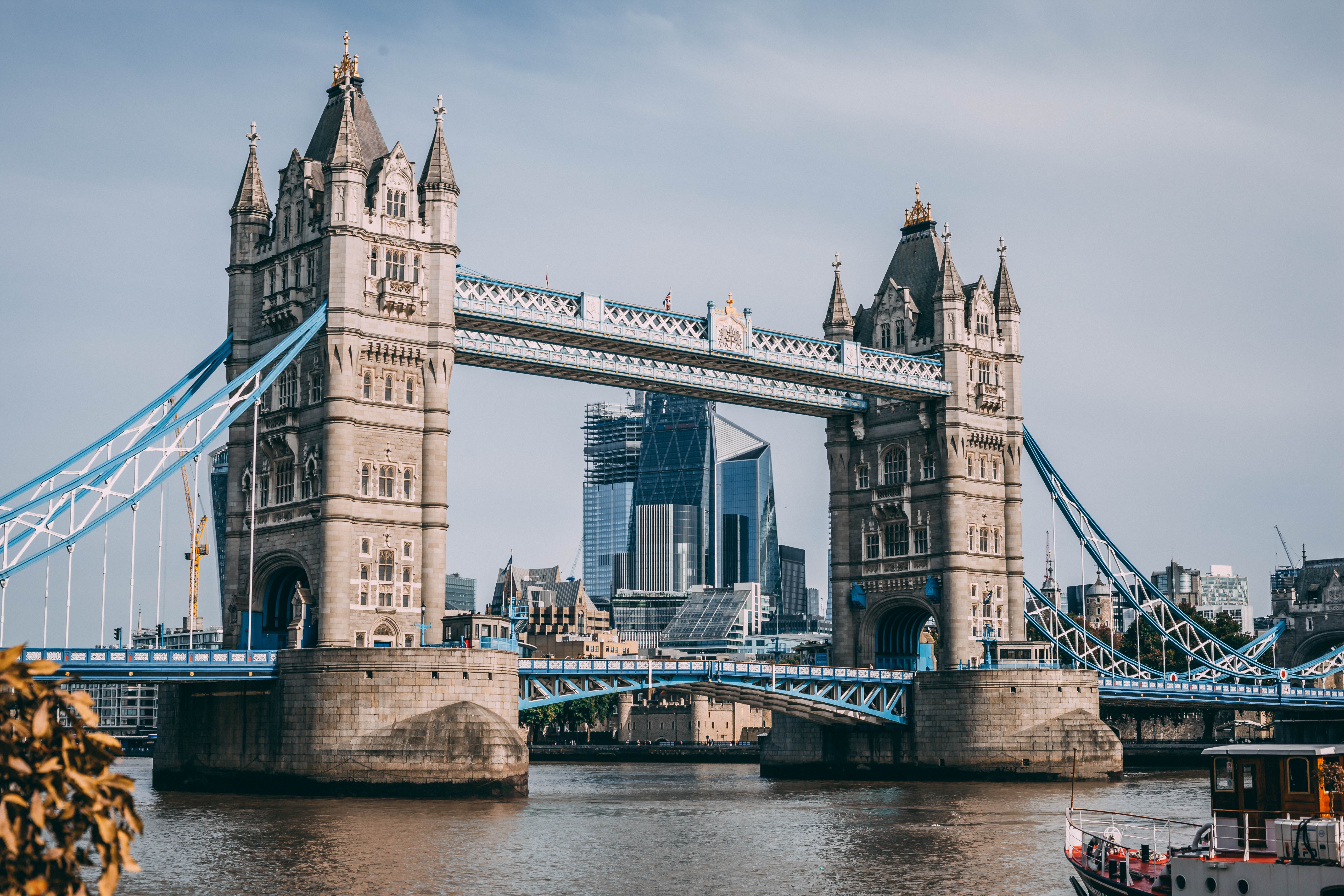 Tower Bridge stretches over the Thames river in London, with two large torrents, crossed by blue roadways.