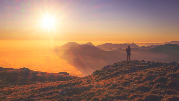 person watching the sunrise over mountains