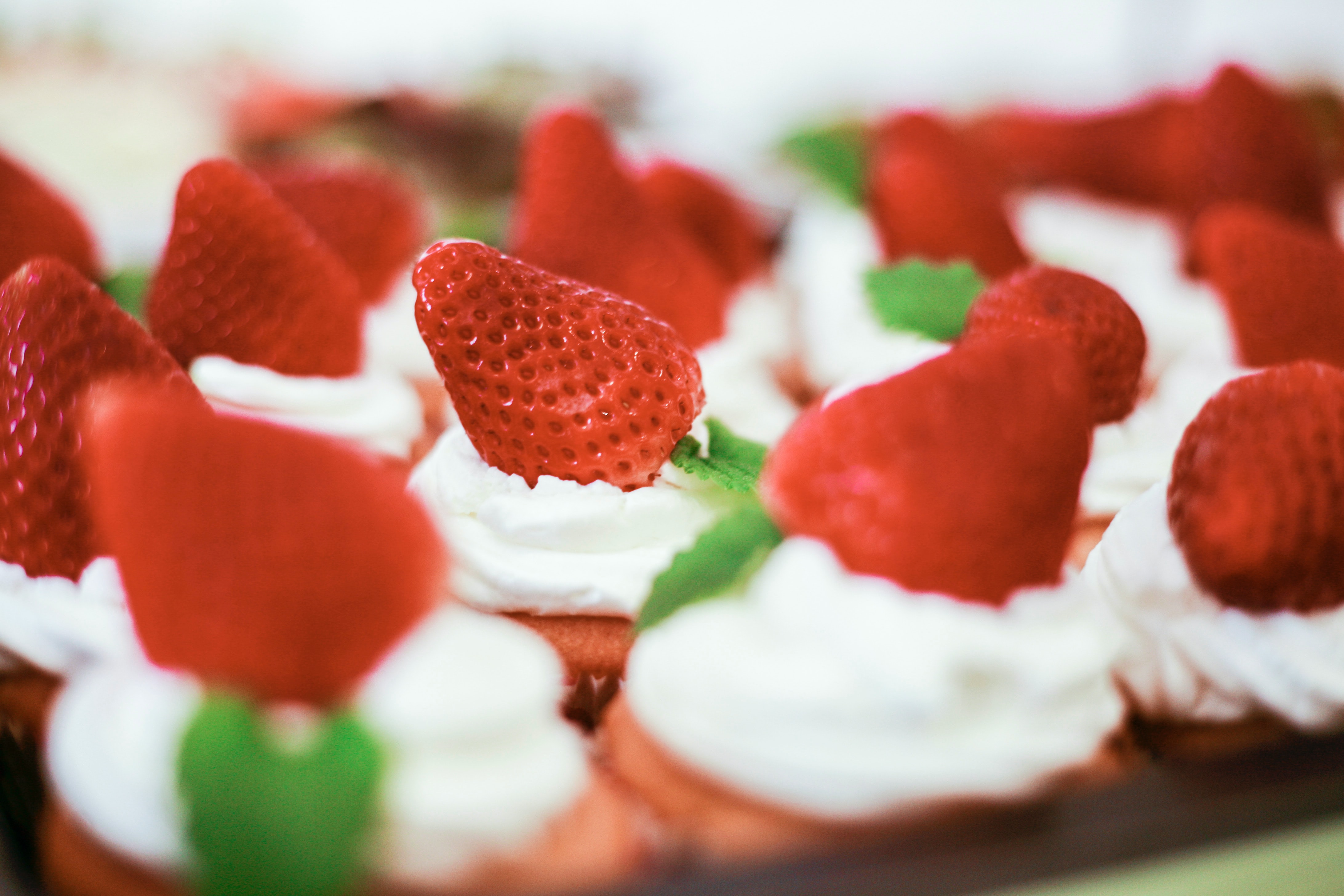 Res strawberries sit on rows of white cream and scones.