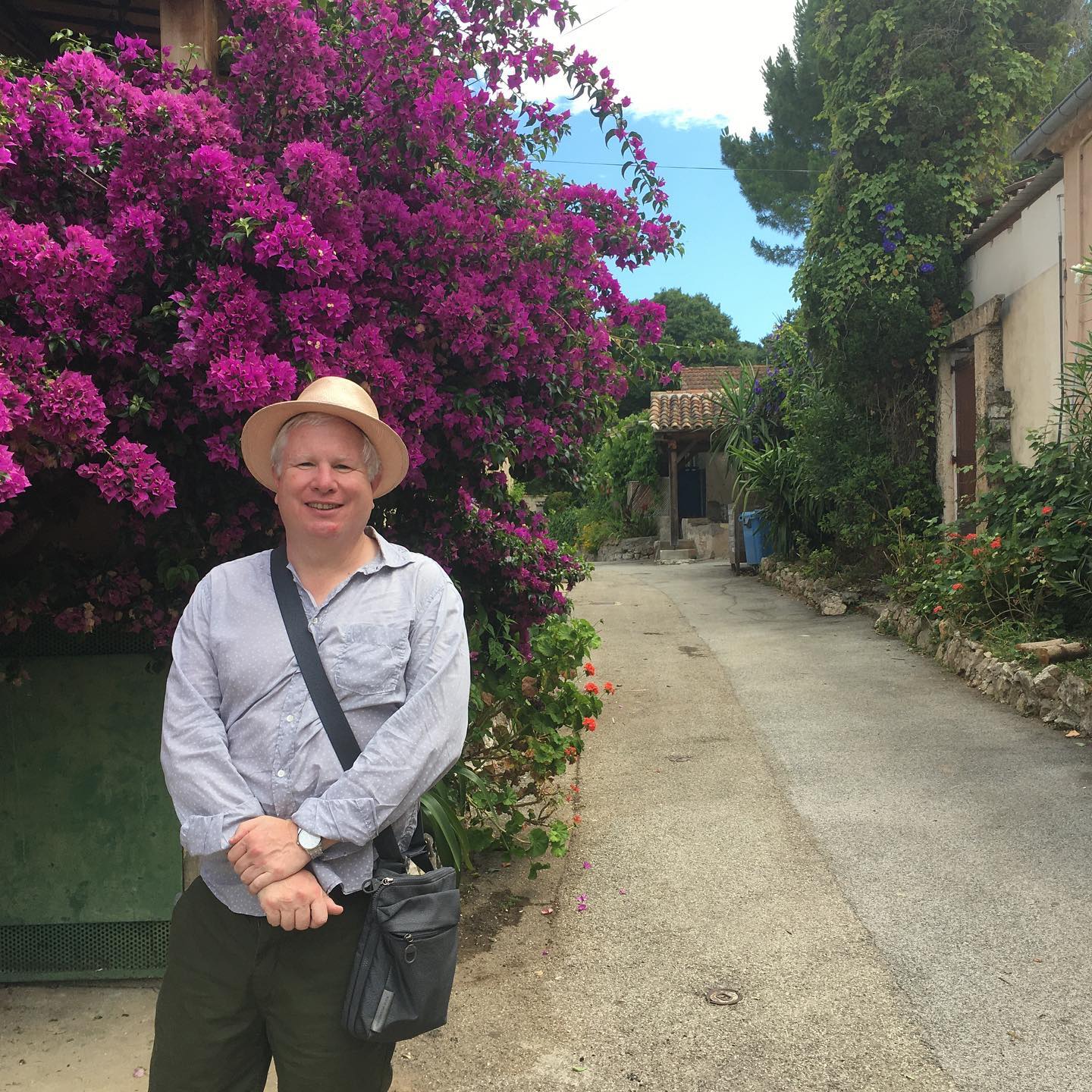 Travel Director Philip stands in front of dark pink blooms at Chelsea Flower Show in London, England