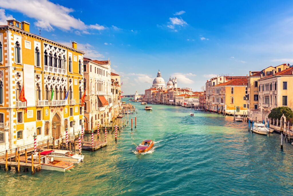 Venice on a sunny evening showing ornate and colourful buildings against the green waters of the canal with a boat passing through