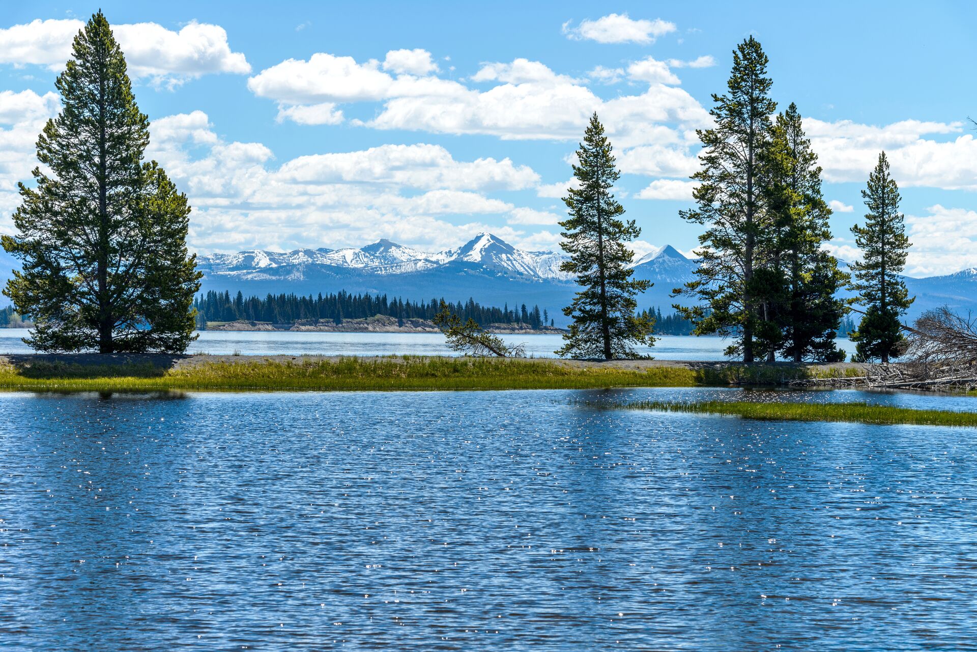 A blue lake flanked by snow caped mountains in Yellowstone National Park, USA