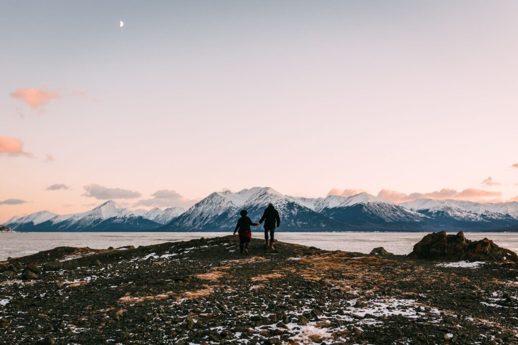 Global travel experts standing on top of a rock with mountains in the background.