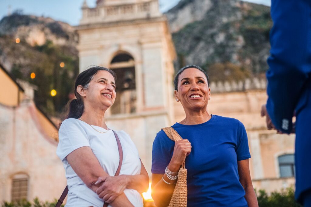 Two female guests, photographed from a low angle, talking to a tour guide (out of frame)
