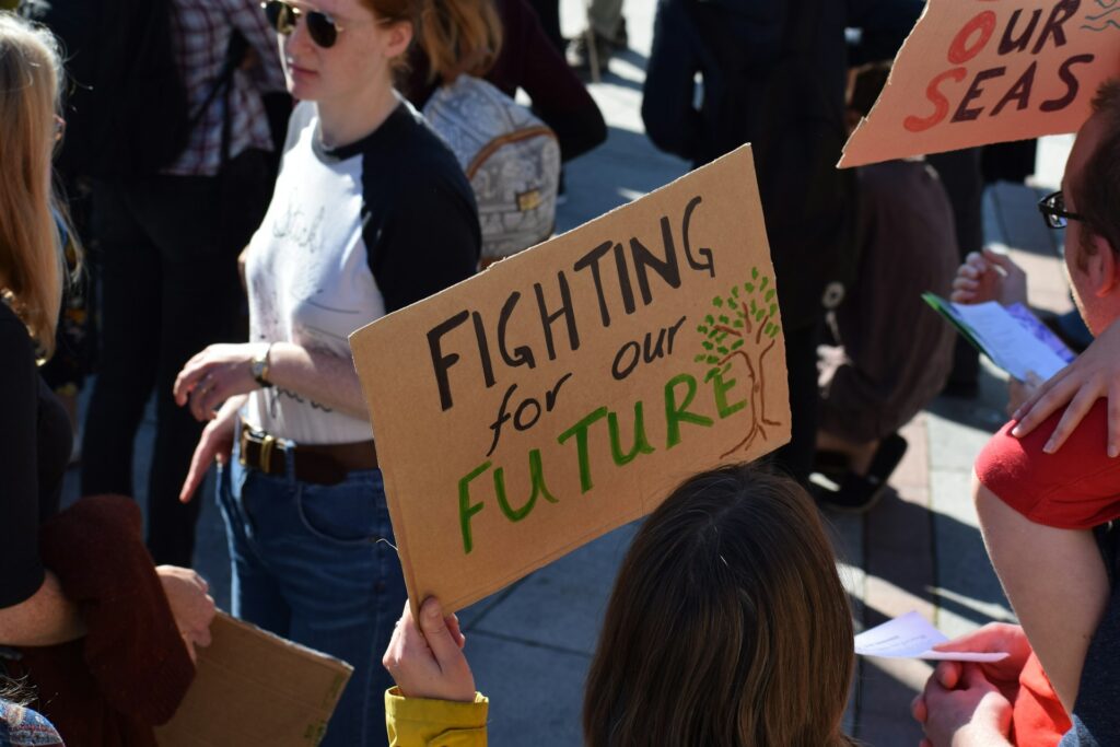 Girl holding up a cardboard sign that reads "fighting for our future"