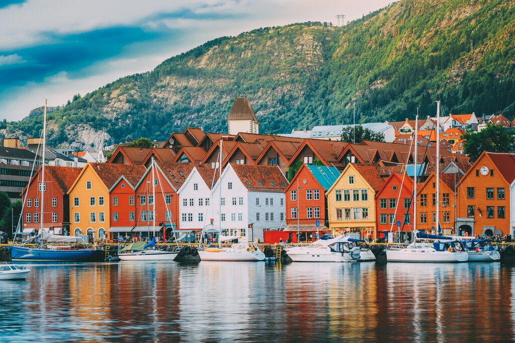 Colourful buildings sit in front of a port, where sailboats lie moored to the promenade