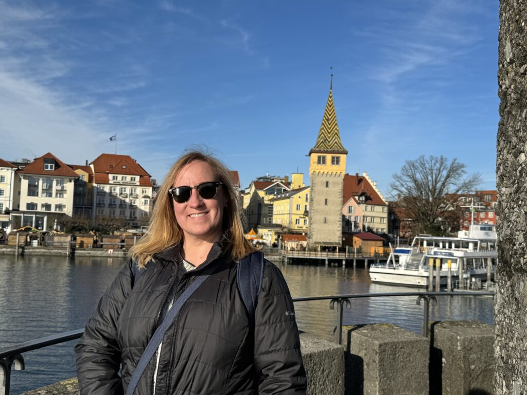 Insightful trivia compeition winner smiles in front of a river with a blue sky.