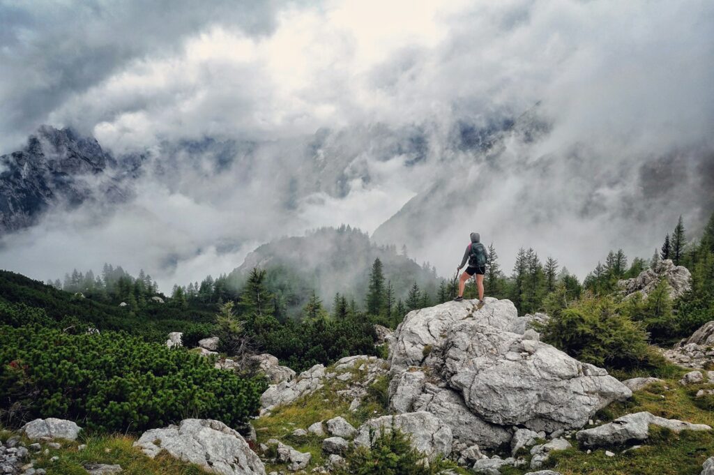Woman standing on rocks overlooking a mountain valley shrouded in clouds
