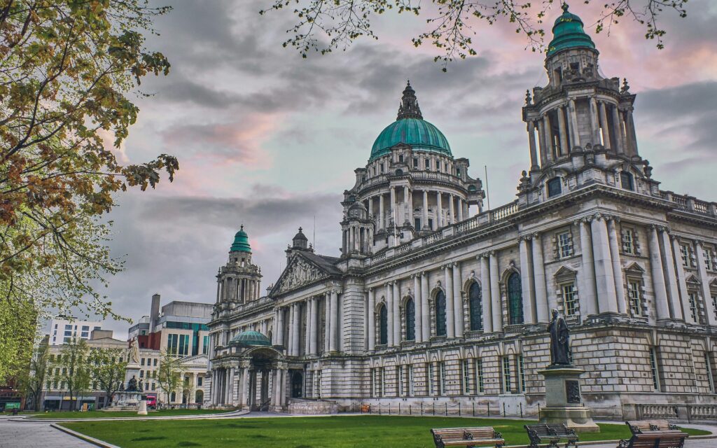 Side view of Belfast City Hall under pink-tinged clouds