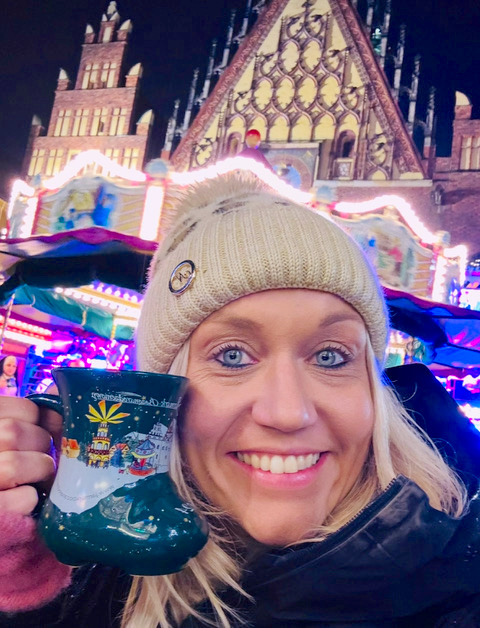 Danielle, Travel Director standing in front of a Christmas market stall holding an ornamental cup