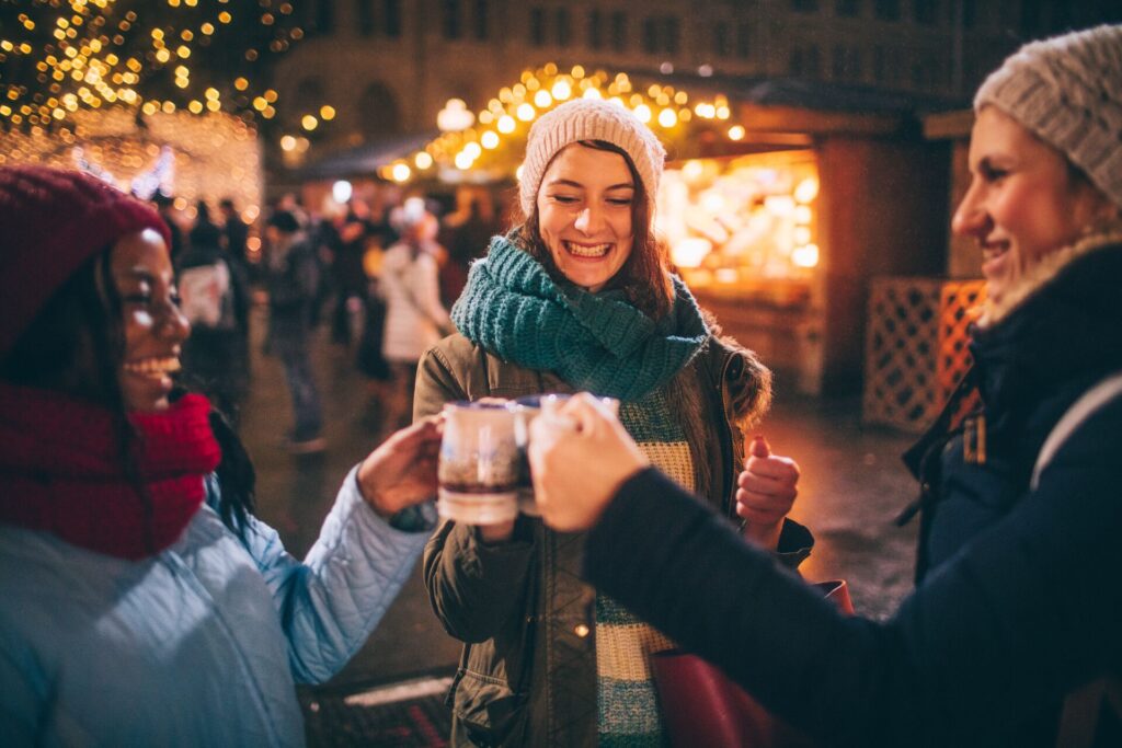 Group of friends enjoying mulled wine in winter market