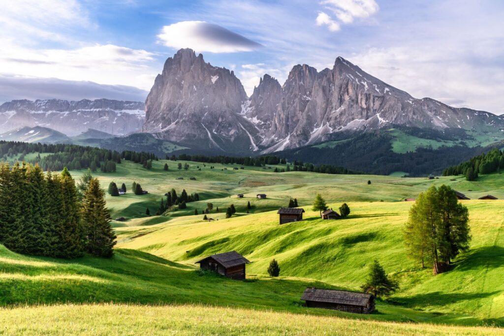 The Dolomite Mountains in Northern Italy with green fields in the foreground.