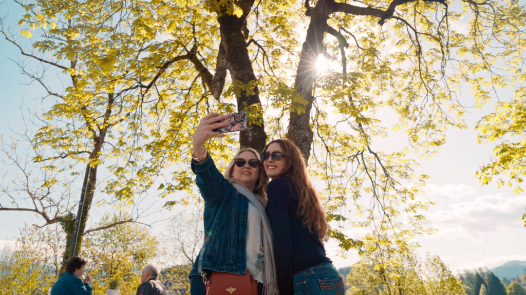 Traveling mother-daughter duo Tammy and Vivian take a selfie in front of a tree.