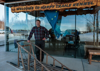 Martin Buser standing next to a sled outside Happy Trails Kennels