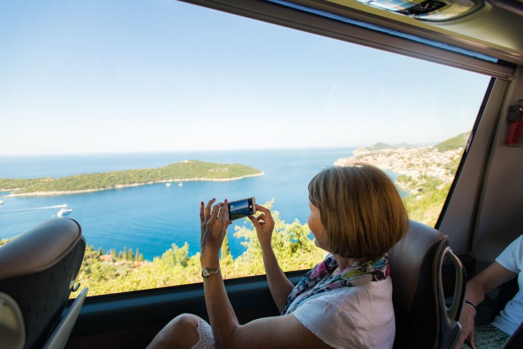A lady relaxes on a coach and takes pictures of the scenery