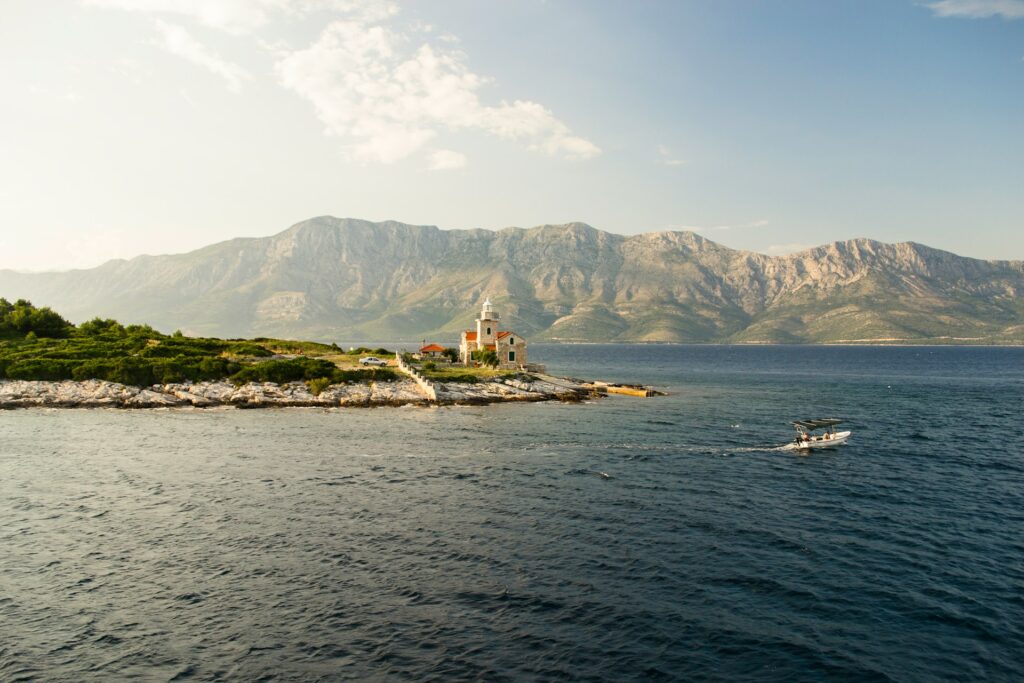 Boat passing a church on the tip of a piece of land in the Adriatic Sea 