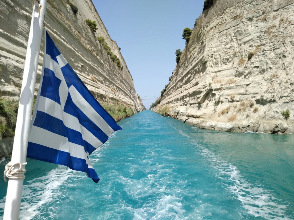View along the Corinth Canal with a Greece flag flying from a flag pole