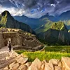 Back view of female tourist descending stairs overlooking Machu Picchu ruins at sunset, Peru
