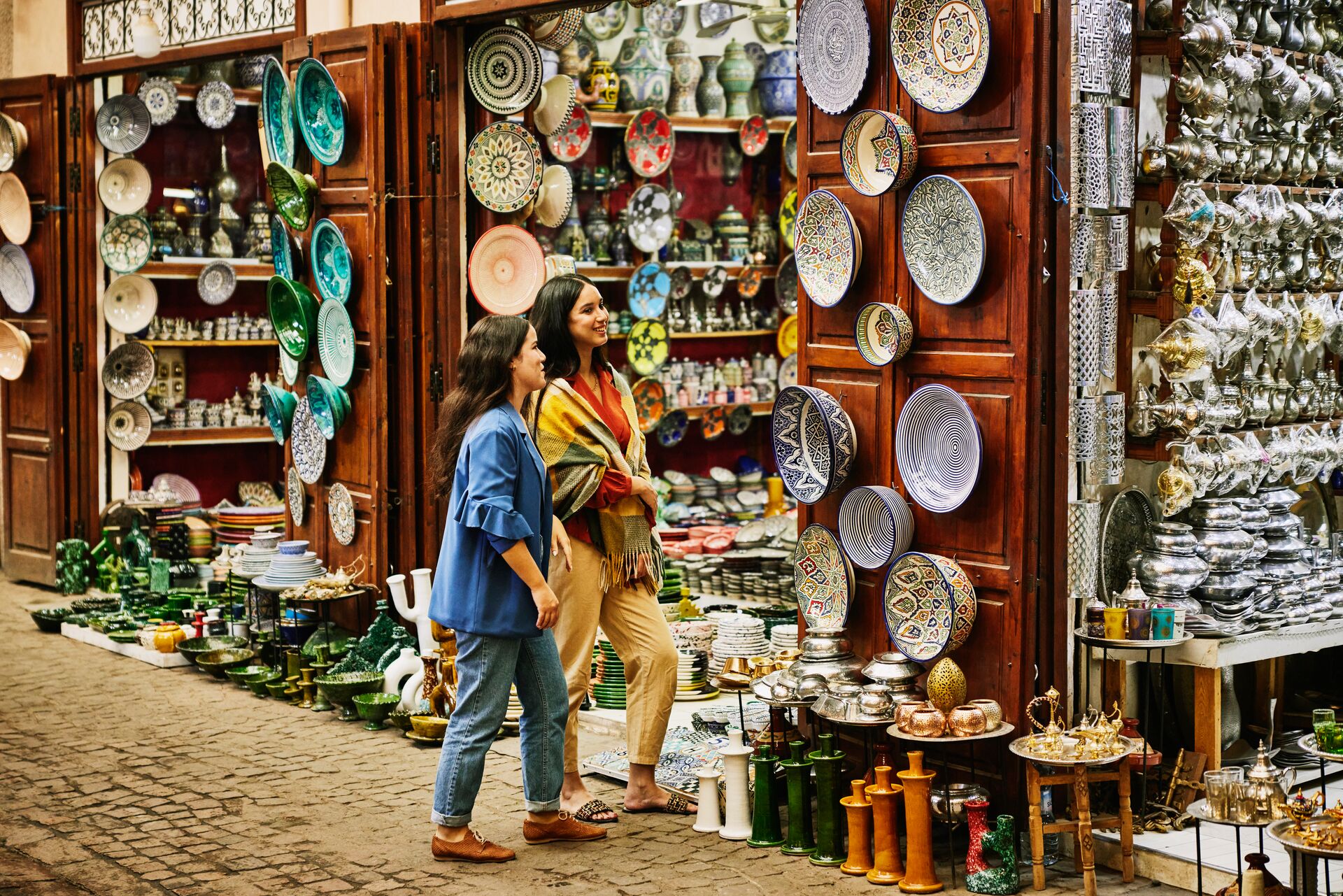 Two female tourists admiring traditional dishes in a souk in Morocco
