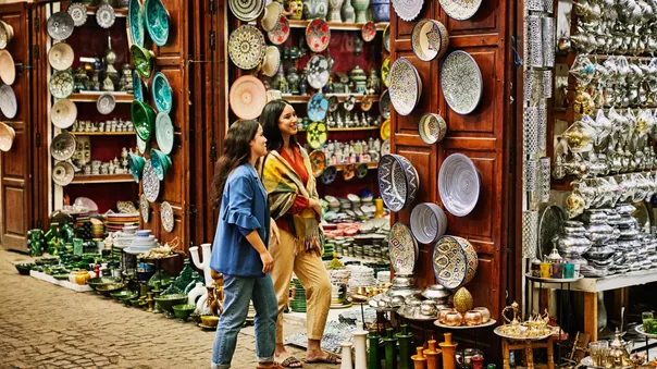 Two female tourists admiring traditional dishes in a souk in Morocco