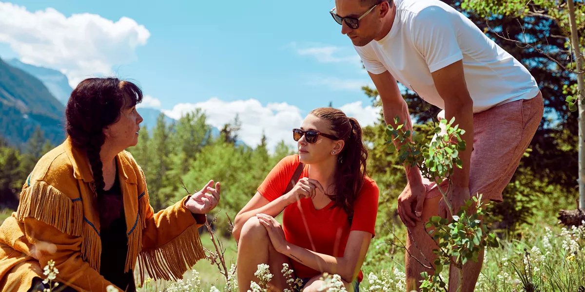 2 tourists learning about local fauna on the Mahikan Trail Plant Medicine Walk in Canmore, Canada