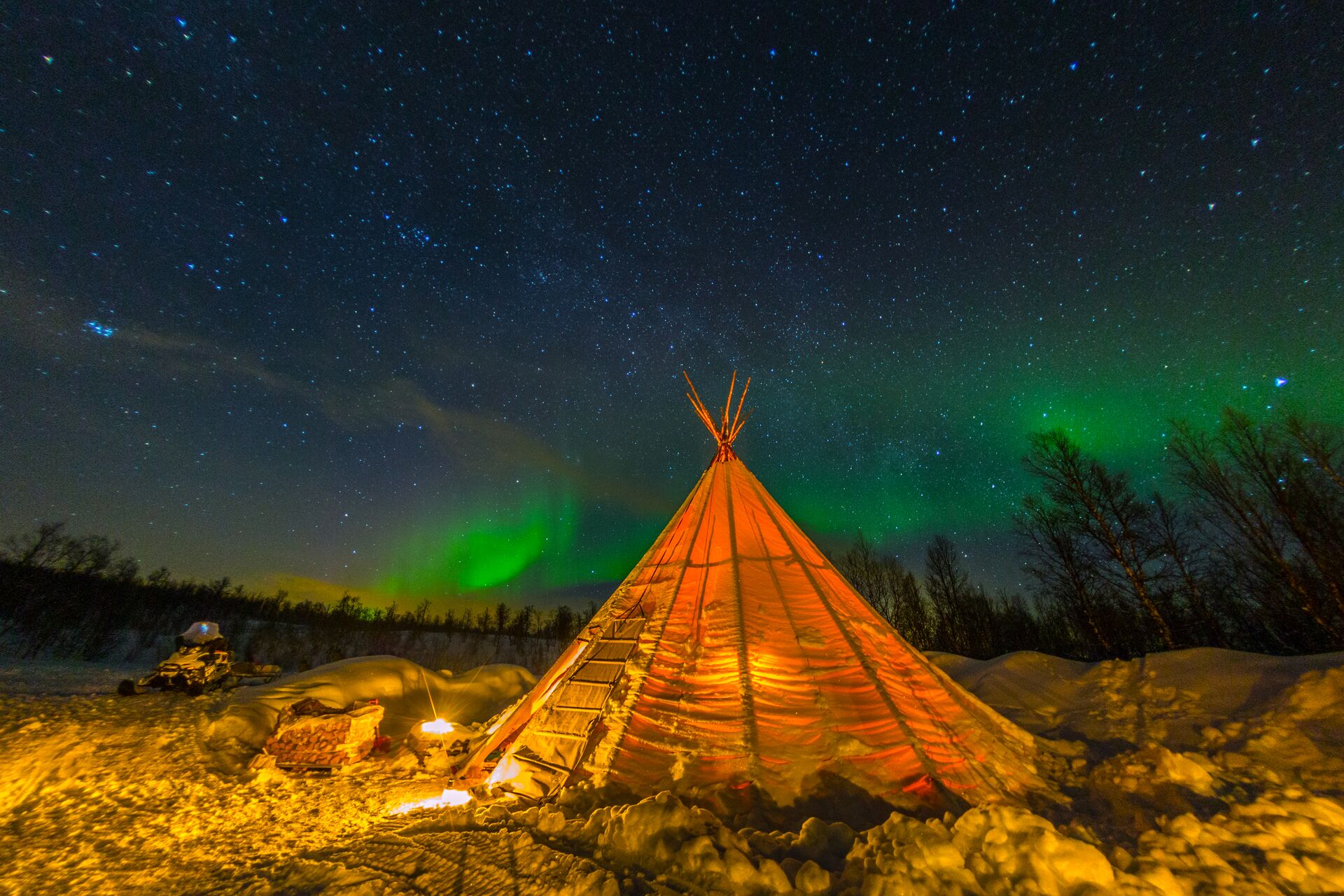 A tipi in Sweden with the Northern Lights shining behind it