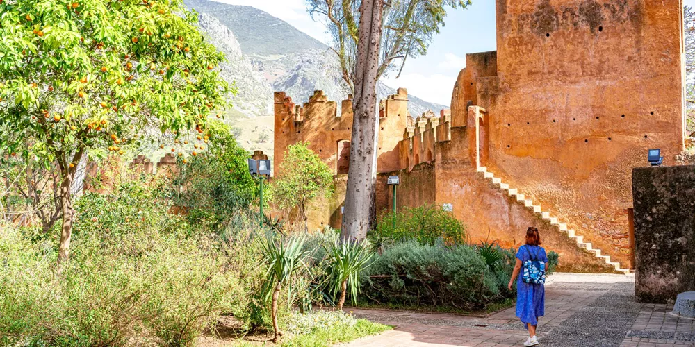 Woman walking to an ancient kasbah fortress in Morocco