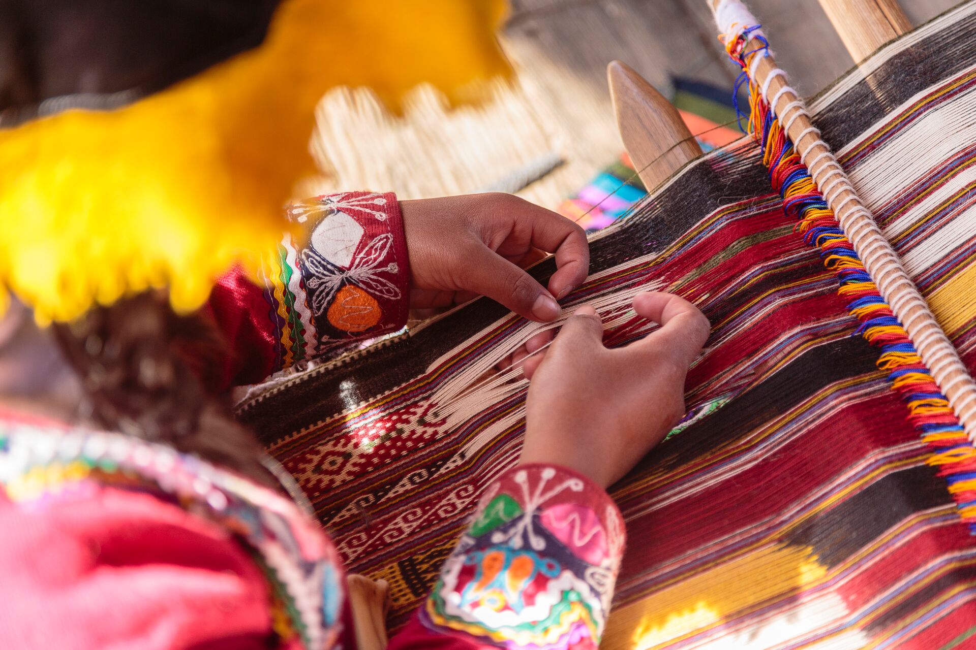 Hands of a woman weaving traditional fabric on a loom in Peru, South America