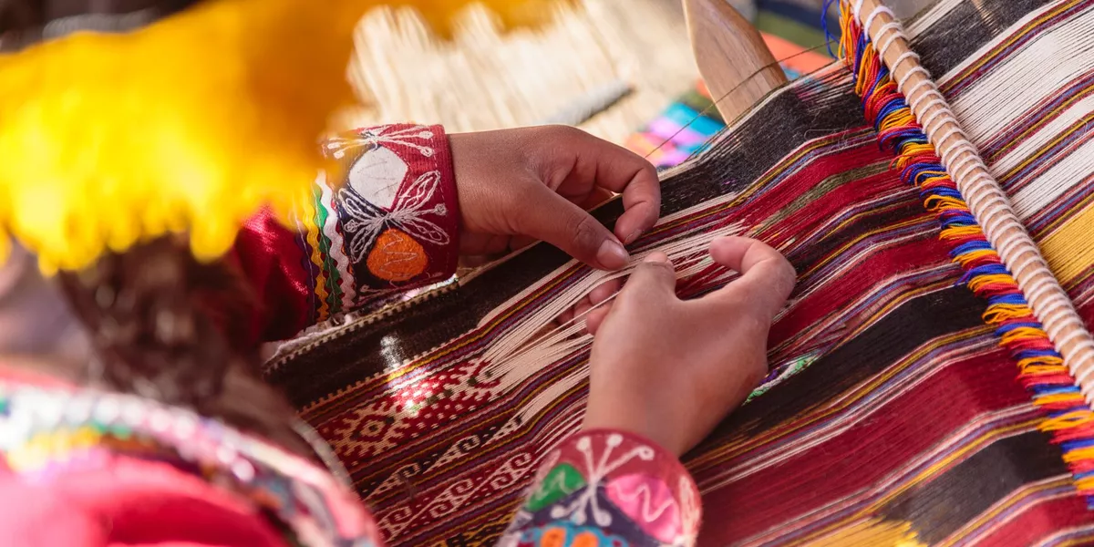 Hands of a woman weaving traditional fabric on a loom in Peru, South America