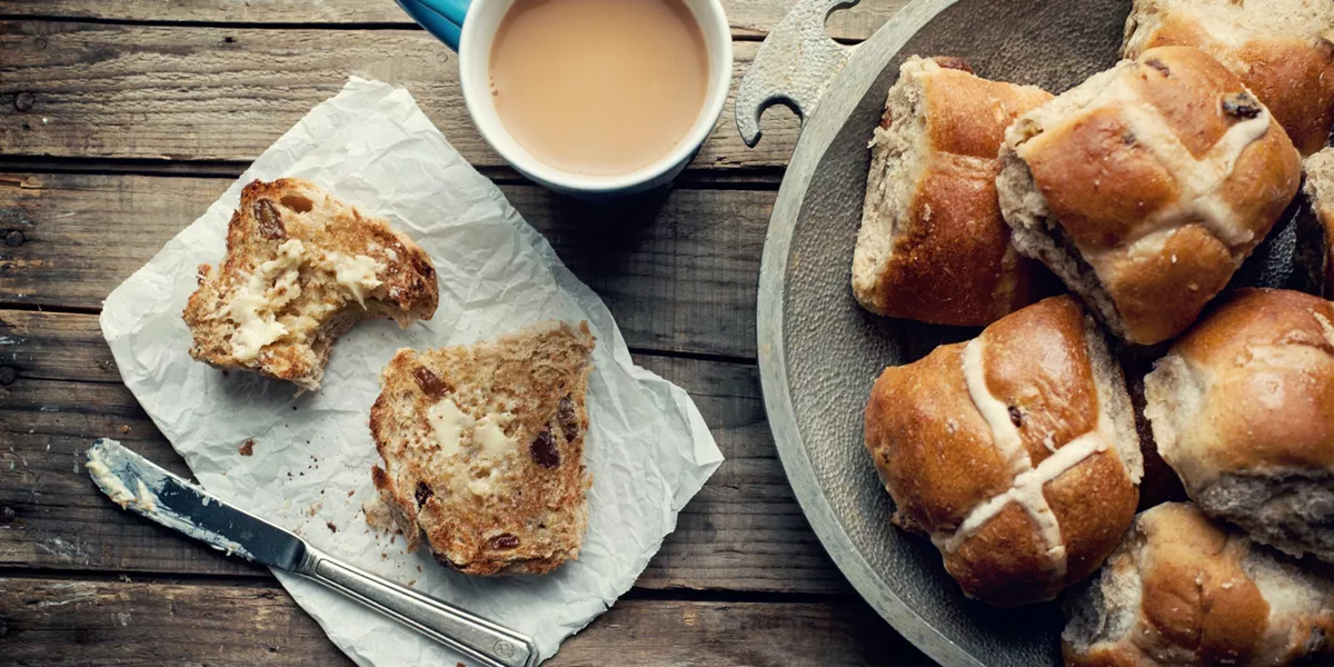 A plate full of hot-cross buns and a mug of coffee.