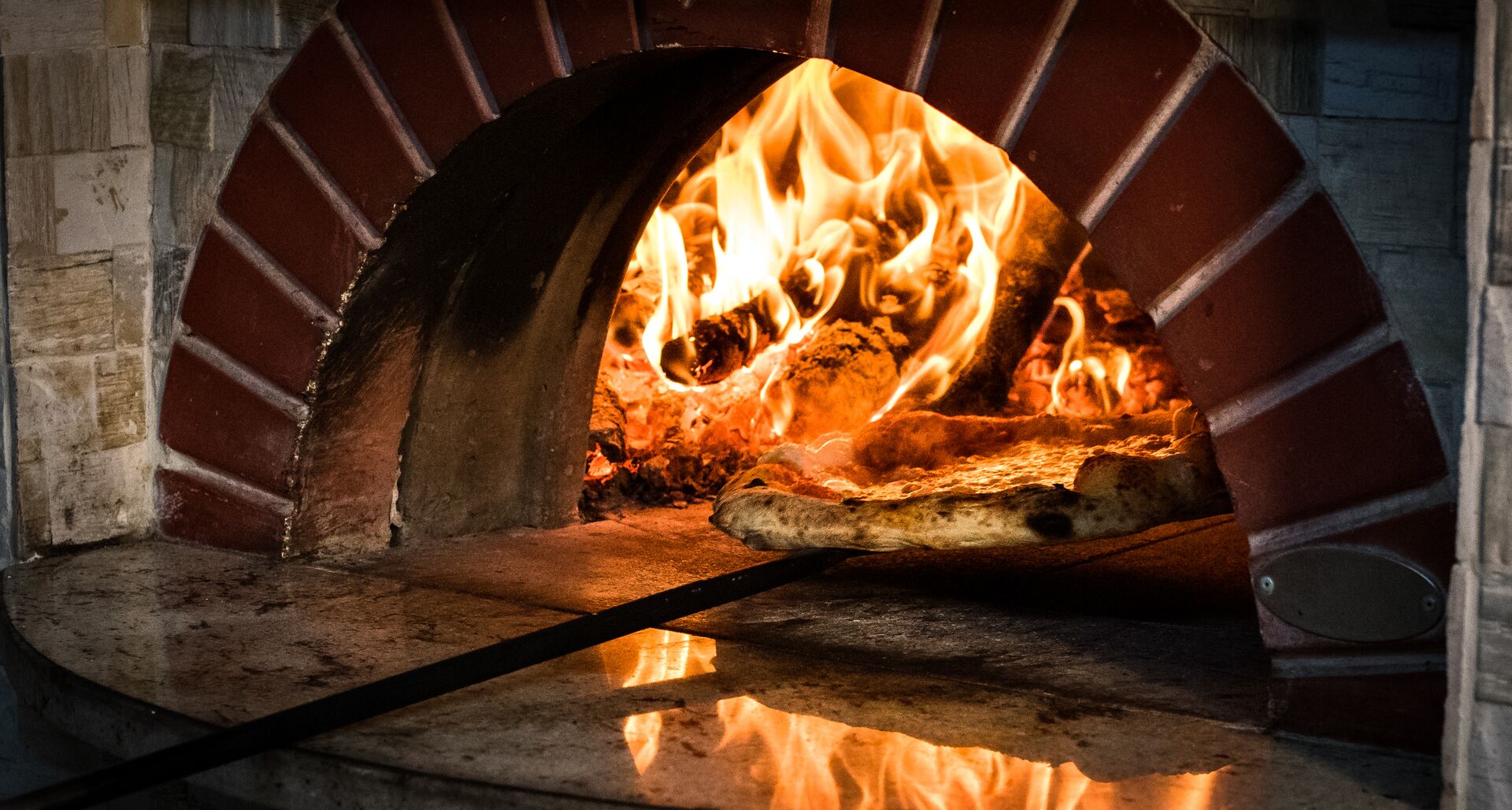 Pizza being removed from stone oven in Italy