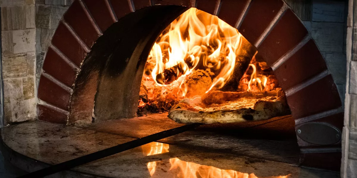 Pizza being removed from stone oven in Italy