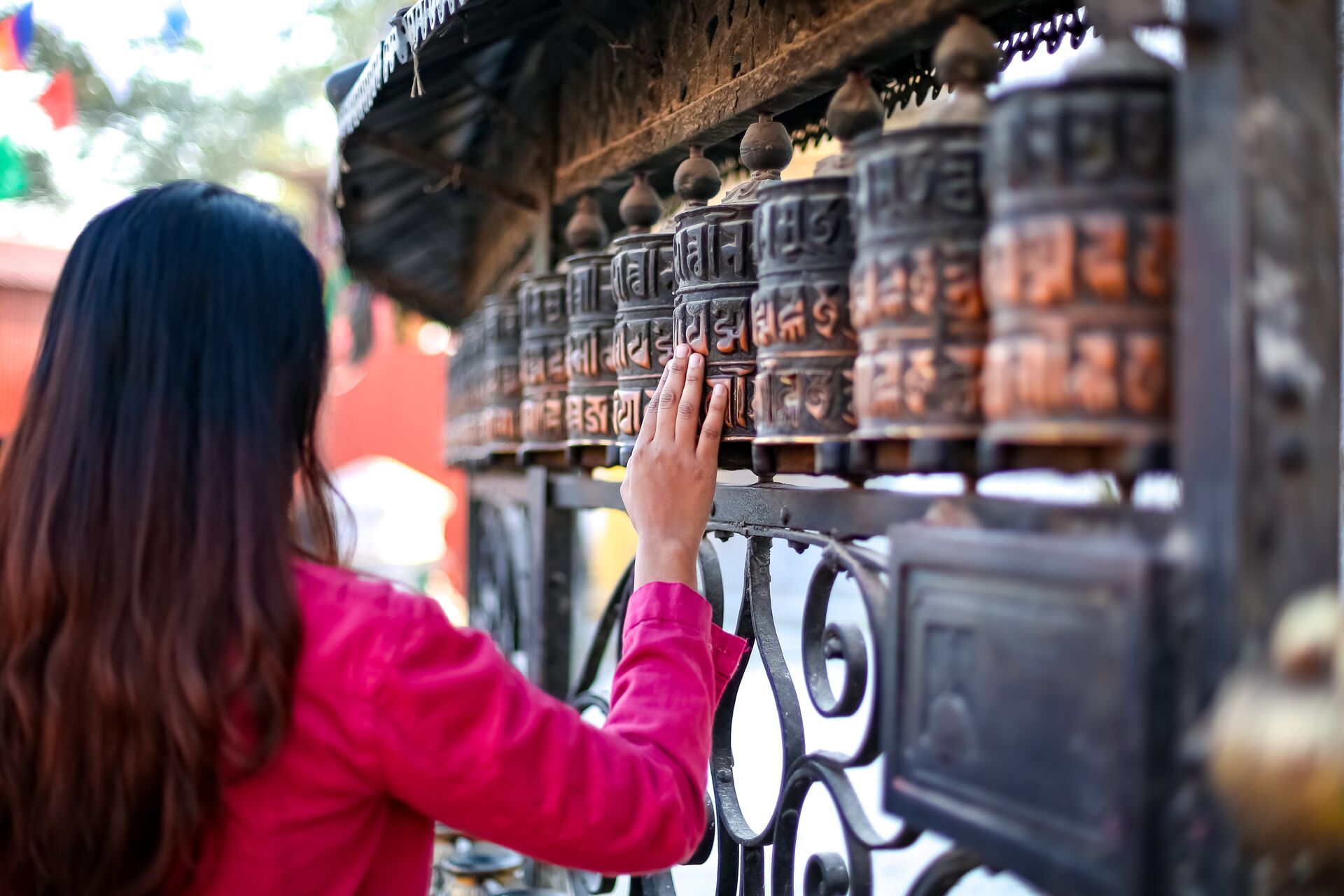Girl passing by a Buddhist prayer wheel in Nepal