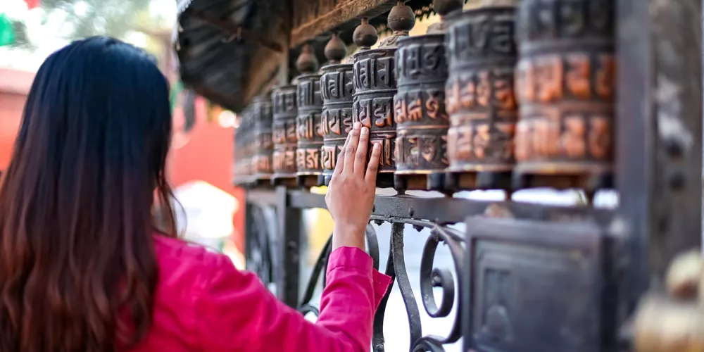 Girl passing by a Buddhist prayer wheel in Nepal