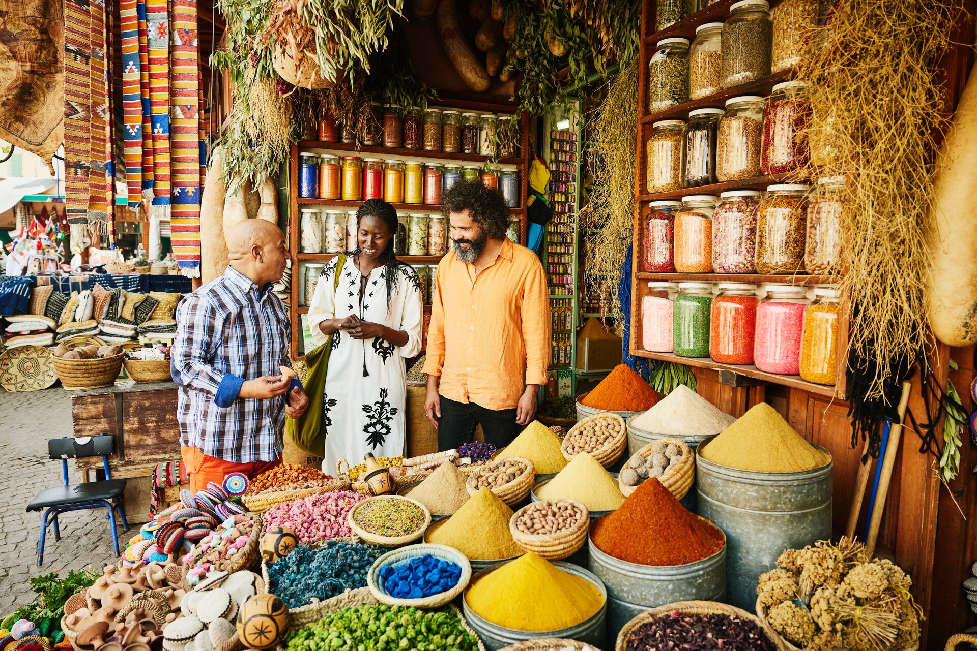 Couple talking to a spice shop owner in the souks of Marrakech, Morocco