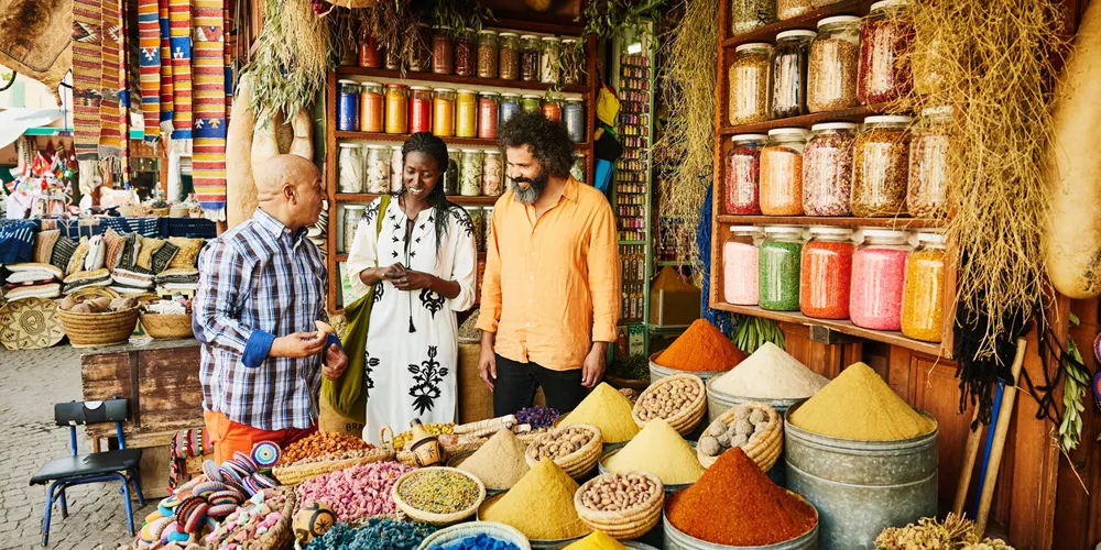 Couple talking to a spice shop owner in the souks of Marrakech, Morocco