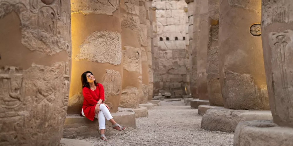 Woman gazing up at the ancient pillars of a temple in Luxor, Egypt