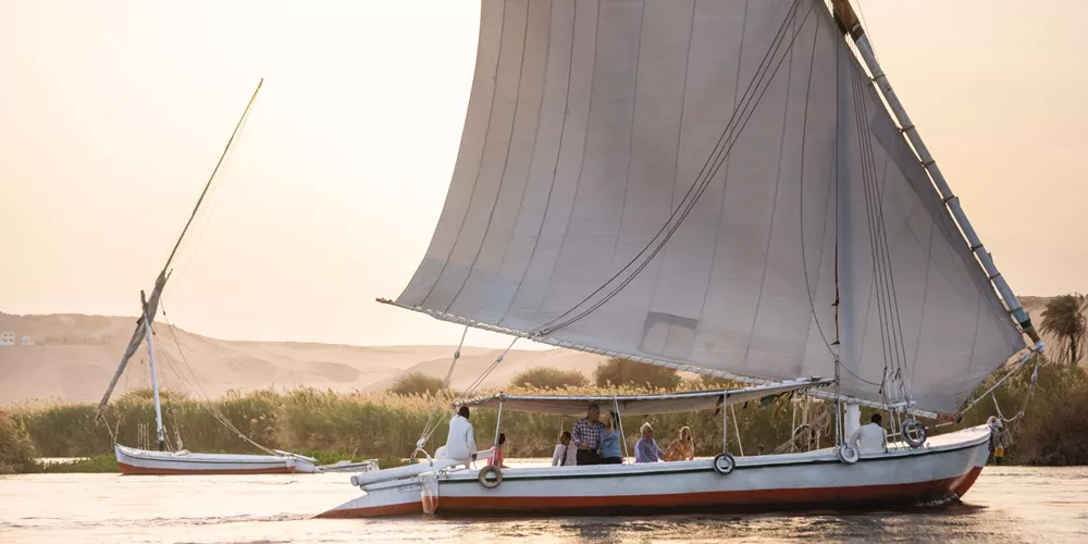 Tourists sailing down the River Nile in Egypt on a traditional Felucca sailing boat