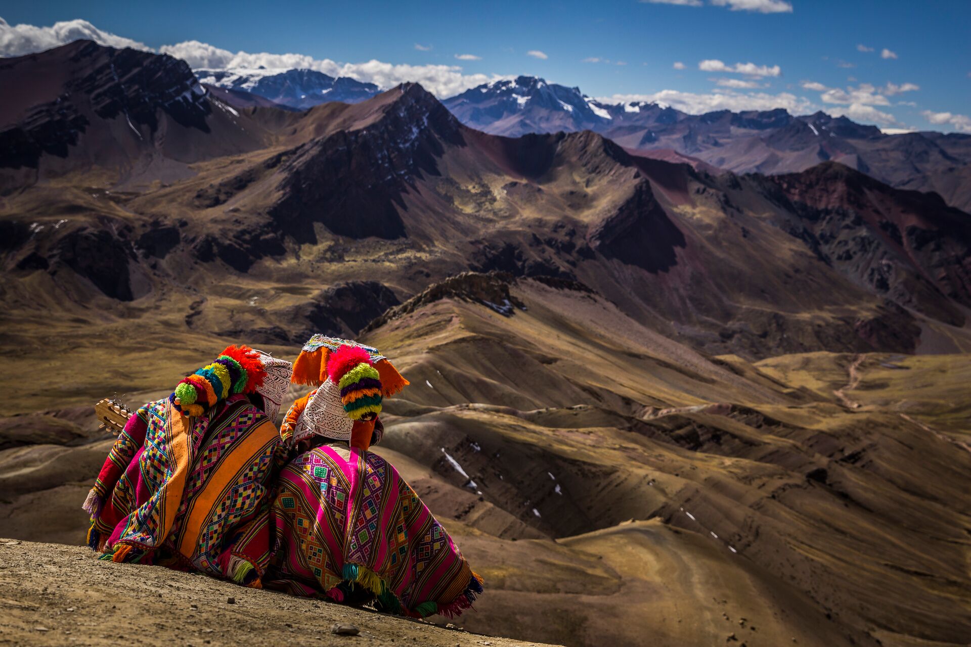 Peruvians in traditional dress looking out at the Andes in Peru, South America