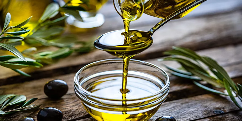 Pouring extra virgin olive oil in a glass bowl