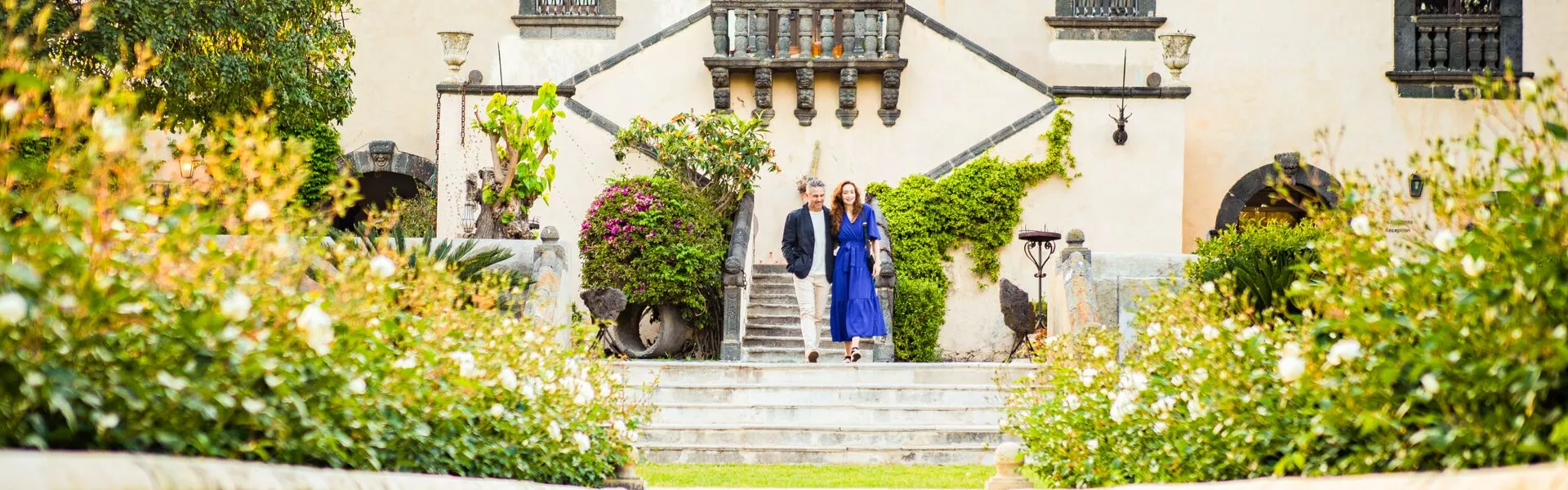 Two guests walk down stone steps outside an Italian building